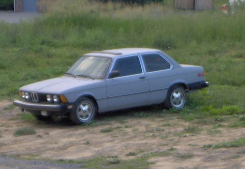 1981 BMW 3 Series - A gray 1981 BMW 3 Series is parked on a dirt patch surrounded by grass.