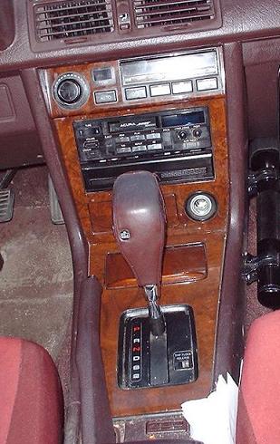 1997 Ford Crown Victoria - The interior of a car shows wood grain trim around the gear shifter and radio console.
