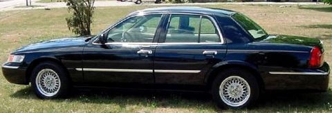 1999 Mercury Grand Marquis - Side view of a black 1999 Mercury Grand Marquis sedan parked on grass.
