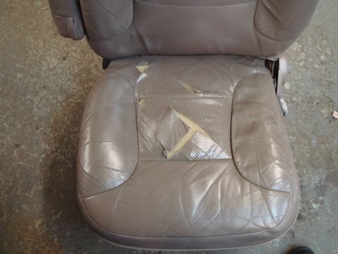 1996 Ford Bronco - A worn tan leather car seat shows extensive damage, with tears revealing the underlying material.