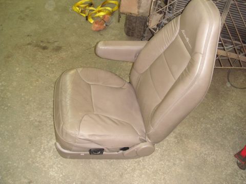 1996 Ford Bronco - A single tan leather car seat with an integrated armrest is shown on a concrete floor.