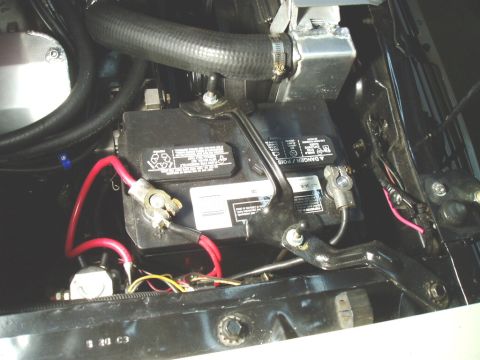 1966 Ford Fairlane - Close-up view of a car battery and radiator hose within the engine compartment.