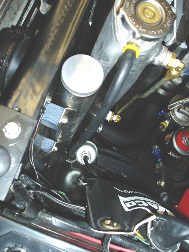 Polished aluminum catch can and chrome radiator filler neck plumbed in an engine bay