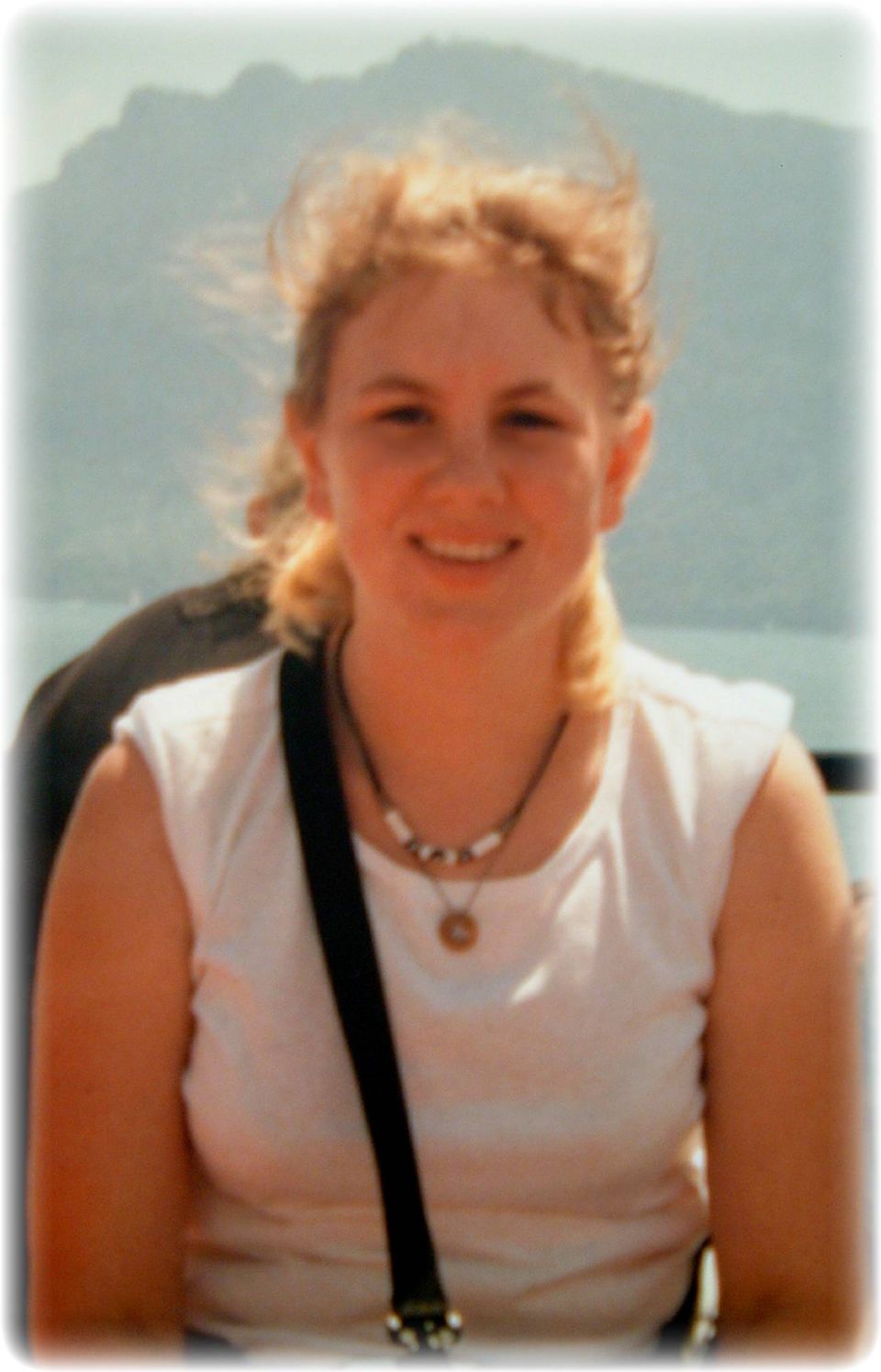 Portrait of a young woman in a white tank top outdoors by water