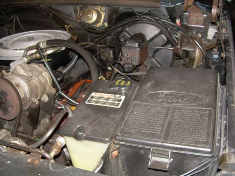 1984 Ford Bronco - Close-up of a 1984 Ford Bronco engine bay, the fuse box and various engine components.