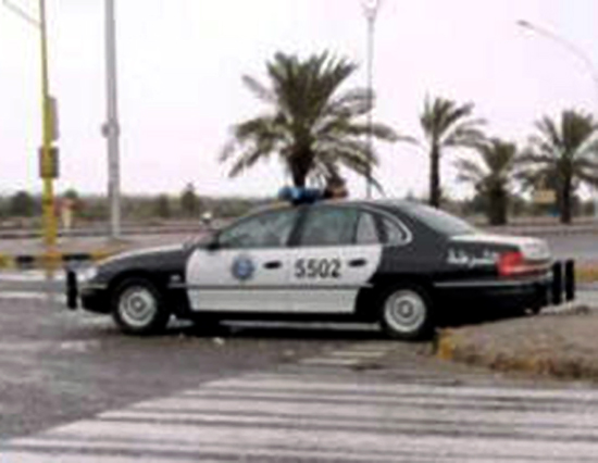 Black-and-white police sedan No. 5502 with Arabic markings parked at a desert crosswalk