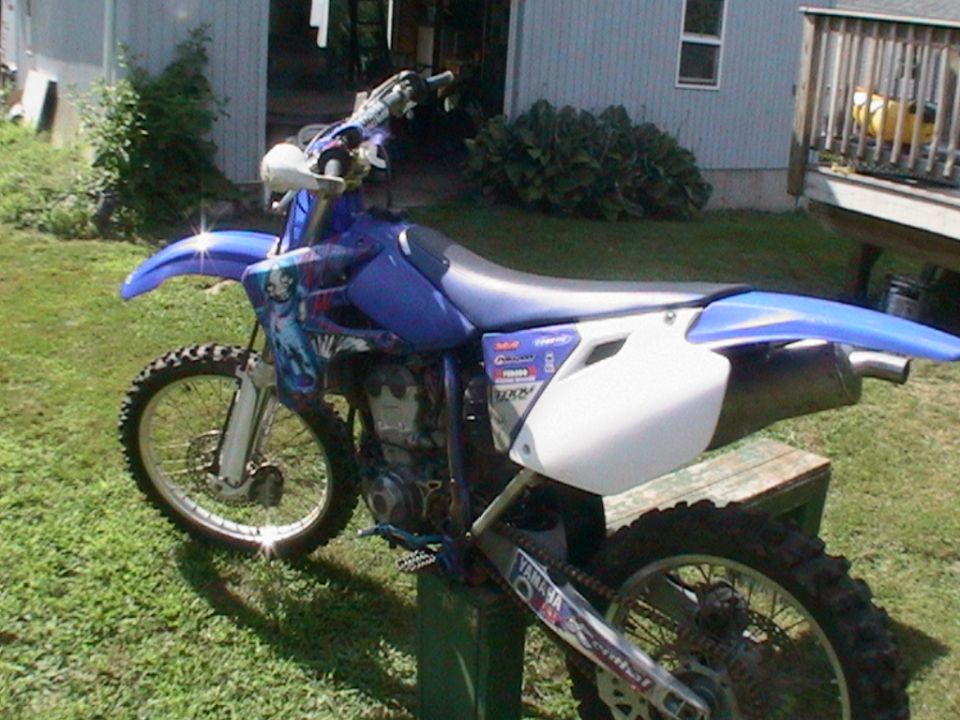 Blue dirt bike with graphics on the side, parked on grass