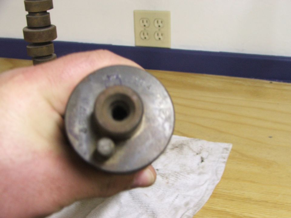 Hand holding a metal automotive part with a hole in the center