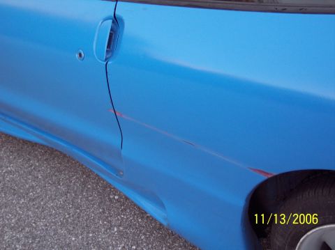 1995 Ford Probe - Scratched blue car door with a visible tire and timestamp overlay.