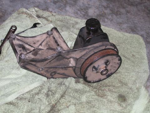1989 Ford Bronco - A dirty power steering pump and its mounting bracket are shown resting on a towel.