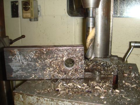 1996 Ford Bronco - A drill press is used to create a hole in a metal block, with metal shavings scattered around the work area.