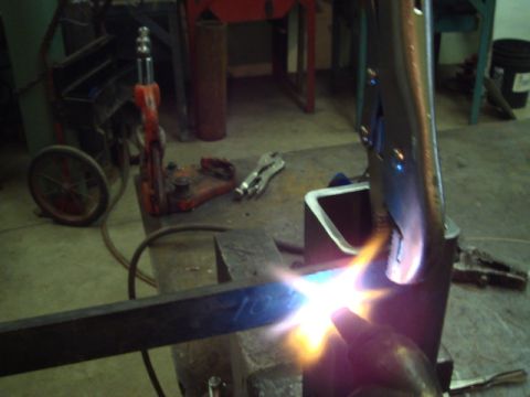 1996 Ford Bronco - A welding torch heats a metal bar held in a vise, with other tools visible in the background.