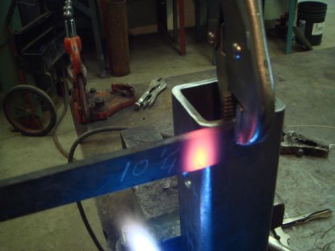 1996 Ford Bronco - Metal fabrication in progress with a torch heating a marked metal bar.