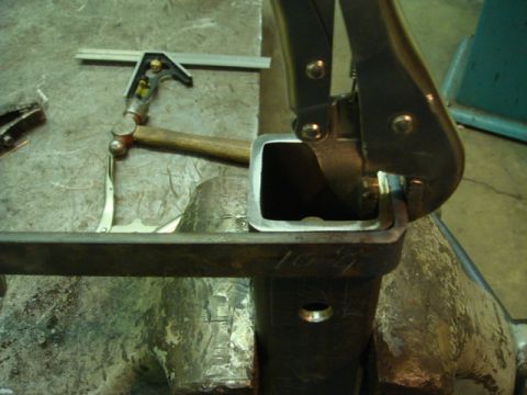 1996 Ford Bronco - A metal part is secured in a vise, with tools like a square and hammer present for fabrication.