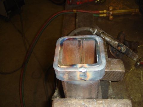 1996 Ford Bronco - A metal part is being worked on with a welding torch in a workshop setting.