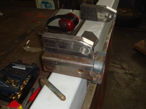 1996 Ford Bronco - Metal hitch receiver assembly with attached bracket, drill bits, and headphones on a workbench.