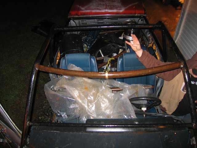Interior view of a roll cage, blue seats, and steering wheel inside a vehicle