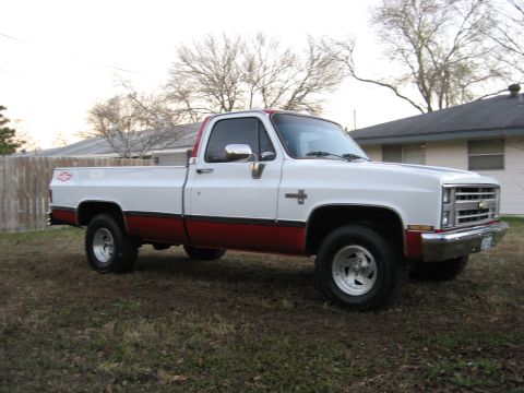 1979 Ford Bronco - This two-tone pickup truck features a white cab and upper bed with a red lower body and trim. The front end styling suggests a 1979 Chevrol…