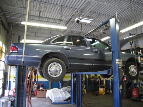 1991 Ford Crown Victoria LTD - A blue 1991 Ford Crown Victoria LTD is raised on a car lift inside a service bay.