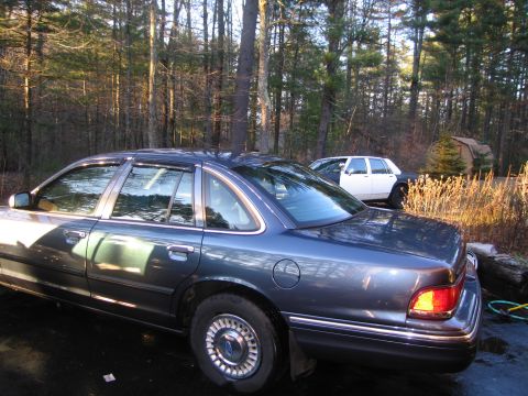 1991 Ford Crown Victoria LTD - A dark blue sedan is parked in a driveway with a white and black car behind it.