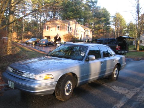 1991 Ford LTD Crown Victoria - A silver 1991 Ford Crown Victoria LTD sedan is parked in a driveway with other vehicles and a house in the background.