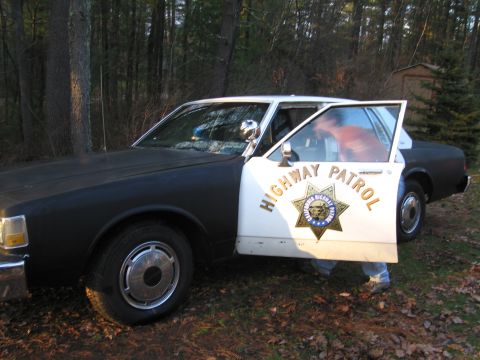 1991 Ford LTD Crown Victoria - A 1991 Ford Crown Victoria LTD police car is parked outdoors with its driver's door ajar.