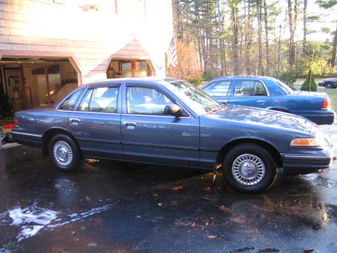 1991 Ford LTD Crown Victoria - Two blue Ford Crown Victoria sedans are parked outside a home. The foreground car is a 1991 model.