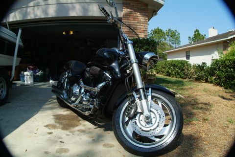 1995 Ford Bronco - A black cruiser motorcycle is parked in front of a suburban garage on a sunny day.