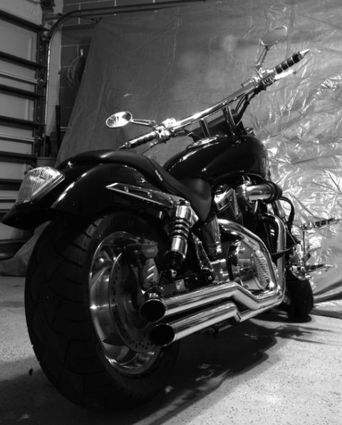1995 Ford Bronco - A black custom motorcycle with chrome details is parked in a garage, viewed from the rear.