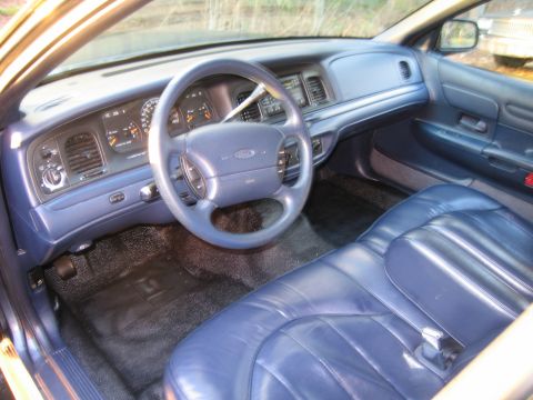 1991 Ford LTD Crown Victoria - The interior of a car is shown, blue leather seats and a dashboard with gauges.