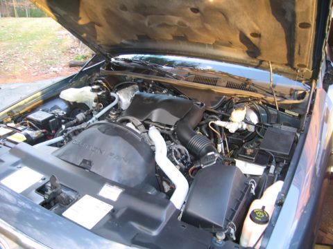 1991 Ford LTD Crown Victoria - The engine bay of a car is shown with the hood open, revealing the engine components and a "CAUTION FAN" warning on the fan shroud.