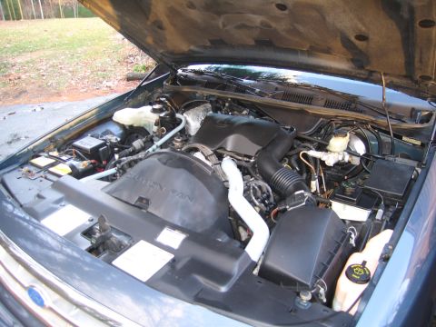 1991 Ford LTD Crown Victoria - The engine bay of a car is open, revealing the motor and associated parts.