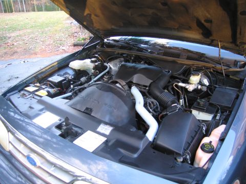 1991 Ford LTD Crown Victoria - The engine bay of a 1991 Ford Crown Victoria LTD is visible with the hood raised, revealing the engine and associated parts.