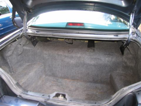 1991 Ford LTD Crown Victoria - The trunk of a 1991 Ford Crown Victoria LTD is shown, revealing its carpeted interior and storage space.