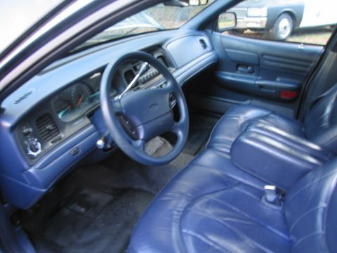 1991 Ford LTD Crown Victoria - Interior view of a 1991 Ford Crown Victoria LTD, showing the dashboard and blue leather seats. Another vehicle is visible outside.