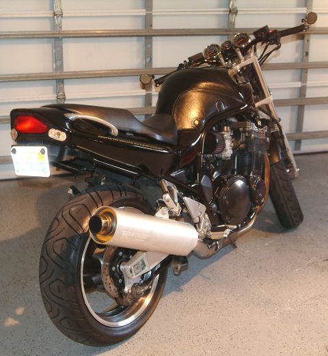 1995 Ford Bronco - A black motorcycle with a large exhaust pipe is parked inside a garage.