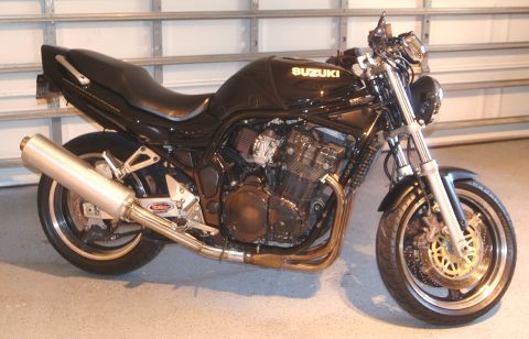 1995 Ford Bronco - A black Suzuki motorcycle is parked in front of a garage door.