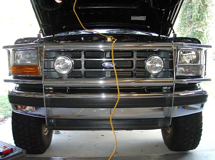 Front grille of a black Ford truck with chrome brush guard and round lights
