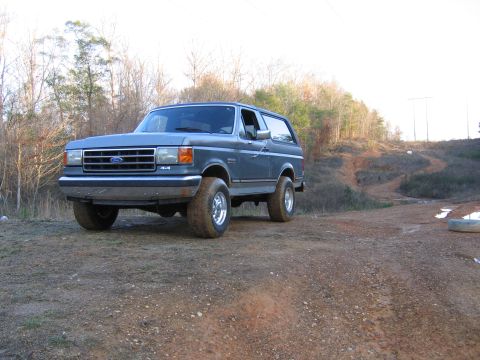 1989 Ford Bronco - This 1989 Ford Bronco is shown in a three-quarter front view on a dirt path with trees in the background.