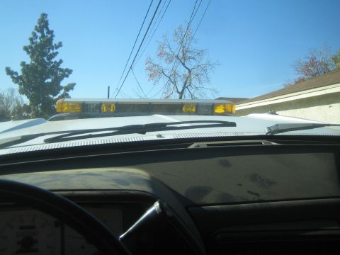 1990 Ford Bronco - Interior view of a vehicle's dashboard with a light bar visible on the roof under a clear sky.