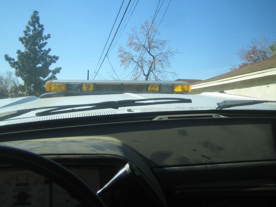 Yellow roof-mounted light bar viewed over a vehicle dashboard against blue sky
