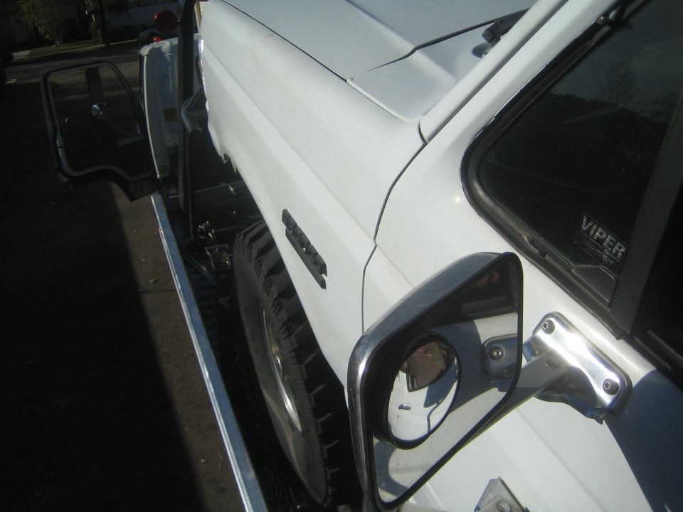 Close-up of a white truck fender, side mirror and off-road tire