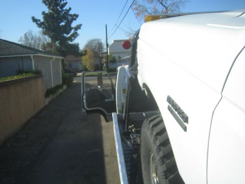 1990 Ford Bronco - A white pickup truck is parked on an asphalt surface with its driver's side door open.