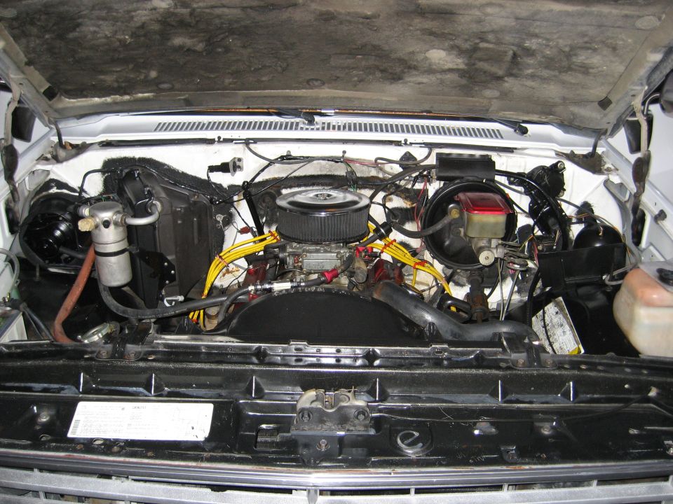 White vehicle engine bay with V8 engine, aftermarket air filter, and yellow spark plug wires