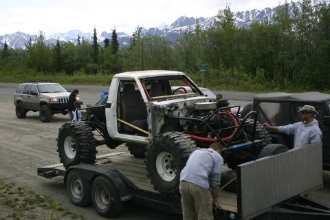2003 Jeep TJ - Custom off-road truck being loaded onto a trailer with mountains in the background.