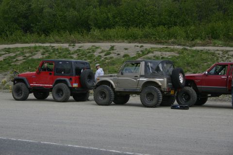 2003 Jeep TJ - A red 2003 Jeep TJ and a tan Suzuki Samurai are parked next to each other on a gravel road.