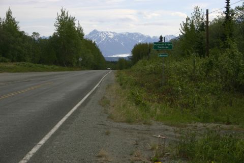2003 Jeep TJ - Scenic view of a road in Alaska with mountains in the distance and a trailhead sign.