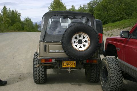 2003 Jeep TJ - Suzuki Samurai parked next to a red Jeep Cherokee at an off-road event.