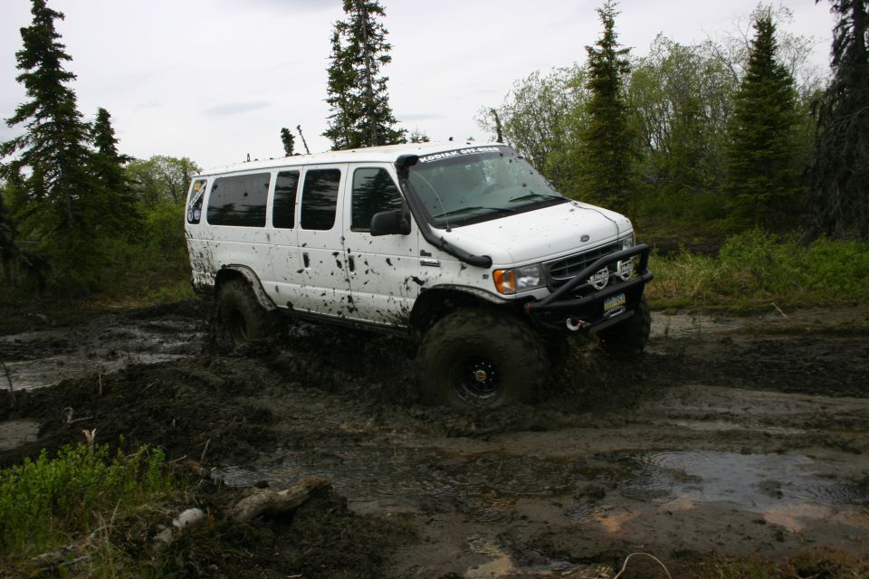 White van with snorkel and off-road bumper stuck in mud, front 3/4 view