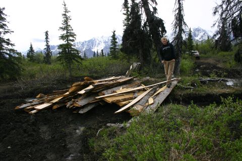 2003 Jeep TJ - A person crosses a makeshift bridge constructed from logs and lumber in a wooded, mountainous area.